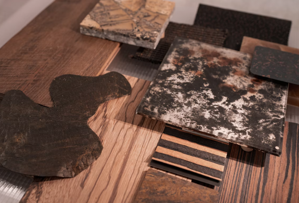 Material samples laid out: wood veneers, dark stone, textured and mottled tile.