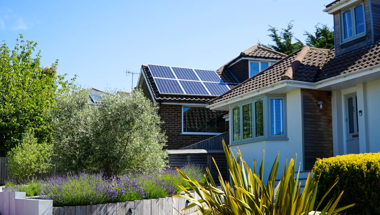 Suburban house, solar array on a tile roof, garden in the foreground.